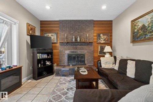 Living area featuring a brick fireplace with a wood mantel, tile flooring, and recessed lighting - 5604 174 Street, Edmonton, AB - Indoor Photo Showing Living Room With Fireplace