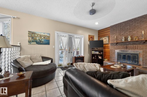 This living space features a brick fireplace, tiled flooring, and French doors - 5604 174 Street, Edmonton, AB - Indoor Photo Showing Living Room With Fireplace