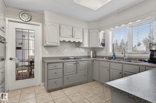The kitchen features light-toned cabinetry, a tiled backsplash, and a double basin sink - 5604 174 Street, Edmonton, AB - Indoor Photo Showing Kitchen With Double Sink