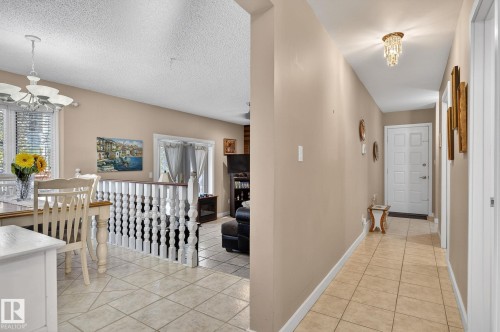 The property features a dining area with a chandelier and large windows, a hallway with tiled flooring and a decorative light fixture, and a white front door - 5604 174 Street, Edmonton, AB - Indoor