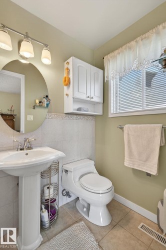 The bathroom features a pedestal sink, a toilet, and light-toned floor tiles - 5604 174 Street, Edmonton, AB - Indoor Photo Showing Bathroom