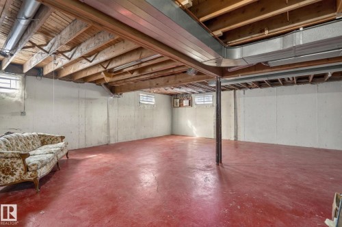 This spacious basement features exposed ceiling beams, concrete walls, and a red concrete floor - 5604 174 Street, Edmonton, AB - Indoor Photo Showing Basement