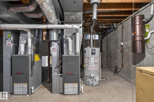 Property utilities including two furnaces and a water heater, alongside exposed ductwork and concrete walls - 5604 174 Street, Edmonton, AB - Indoor Photo Showing Basement