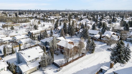 Aerial view of the neighborhood featuring snow-covered rooftops, mature trees, and a distant cityscape under a clear sky - 5604 174 Street, Edmonton, AB - Outdoor With View