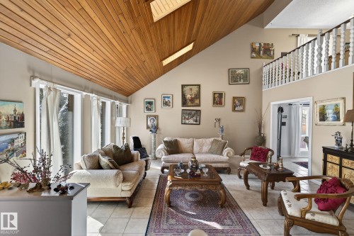 This inviting living area features a vaulted wood-paneled ceiling, large windows, and tile flooring - 5604 174 Street, Edmonton, AB - Indoor Photo Showing Living Room