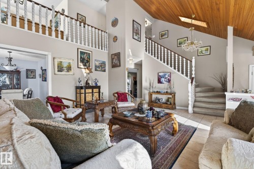 The property features a spacious living area with high ceilings, a prominent staircase, and a wood-paneled ceiling - 5604 174 Street, Edmonton, AB - Indoor Photo Showing Living Room