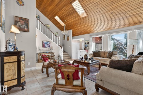 The living area features a vaulted wood-paneled ceiling with skylights, large windows, and tiled flooring - 5604 174 Street, Edmonton, AB - Indoor Photo Showing Living Room
