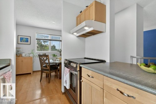 The kitchen features light wood cabinetry, a stainless steel range with an overhead hood fan, and durable countertops - 2655 89 Street, Edmonton, AB - Indoor Photo Showing Kitchen