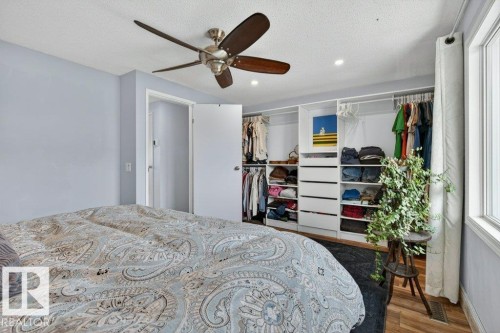 The property features a bedroom with a ceiling fan, recessed lighting, a window providing natural light, and a custom closet organization system with shelving and drawers - 2655 89 Street, Edmonton, AB - Indoor Photo Showing Bedroom