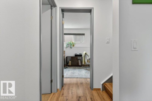 The property features light-colored walls, a wood floor, and a doorway leading into a room with a window - 2655 89 Street, Edmonton, AB - Indoor Photo Showing Other Room