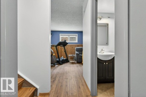 This property features a lower level with wood-look flooring and a window, offering a versatile space - 2655 89 Street, Edmonton, AB - Indoor Photo Showing Other Room