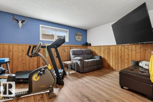 A versatile room featuring wood paneling, wood-style flooring, and a window providing natural light - 2655 89 Street, Edmonton, AB - Indoor Photo Showing Gym Room