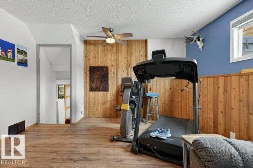 This versatile room features wood paneling, a ceiling fan, and durable flooring, offering a functional and adaptable space within the property - 2655 89 Street, Edmonton, AB - Indoor Photo Showing Gym Room