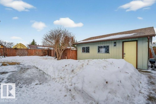 The property features a detached building with light green siding and a brown shingled roof, complete with a yellow exterior door and two windows - 2655 89 Street, Edmonton, AB - Outdoor