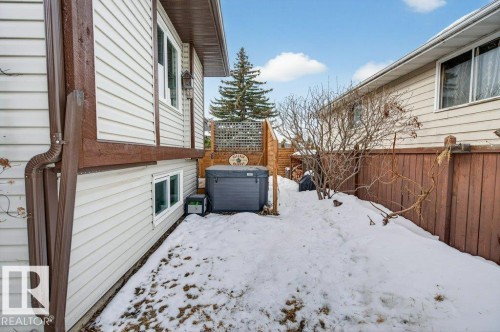 The property features a private outdoor area with a hot tub and a wooden fence - 2655 89 Street, Edmonton, AB - Outdoor With Exterior