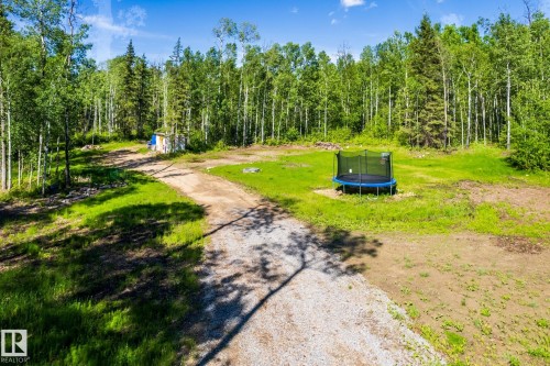 Expansive gravel drive leading to a clearing surrounded by mature deciduous and evergreen trees - 17 56110 Rge Road 13, Rural Lac Ste. Anne County, AB 