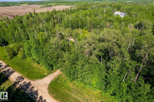 Expansive wooded property featuring a visible residence with a light-colored exterior and gabled roofline - 17 56110 Rge Road 13, Rural Lac Ste. Anne County, AB 