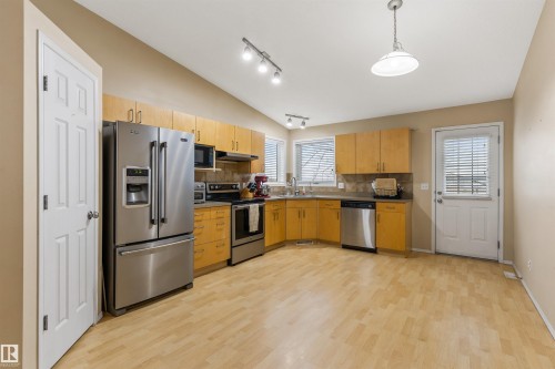 The kitchen features light wood cabinetry, stainless steel appliances, and a light-colored flooring - 1233 Ormsby Lane, Edmonton, AB - Indoor Photo Showing Kitchen