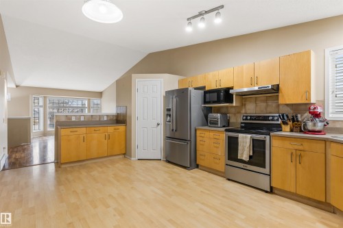 The kitchen features light wood cabinetry, stainless steel appliances, and light wood flooring - 1233 Ormsby Lane, Edmonton, AB - Indoor Photo Showing Kitchen