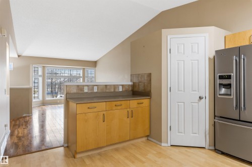 Kitchen area featuring light wood flooring and cabinetry with a stone-look countertop and tiled backsplash - 1233 Ormsby Lane, Edmonton, AB - Indoor Photo Showing Kitchen