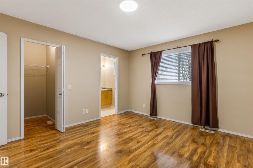 This room features wood-look flooring, neutral wall colors, and a window with blinds and curtains - 1233 Ormsby Lane, Edmonton, AB - Indoor Photo Showing Other Room