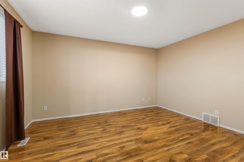 This room features wood-look flooring, light-colored walls, and a window with blinds and dark curtains - 1233 Ormsby Lane, Edmonton, AB - Indoor Photo Showing Other Room