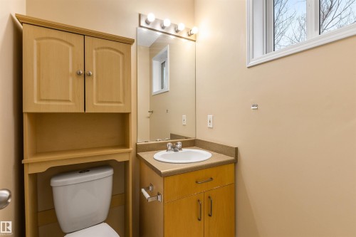 Bathroom featuring a vanity with an integrated sink, a mirror with overhead lighting, and an over-the-toilet storage unit - 1233 Ormsby Lane, Edmonton, AB - Indoor Photo Showing Bathroom