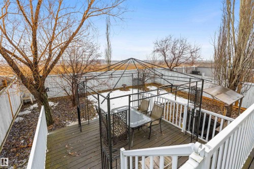 The property features a fenced backyard with a wooden deck, a gazebo, and scattered trees - 1233 Ormsby Lane, Edmonton, AB - Outdoor With Deck Patio Veranda