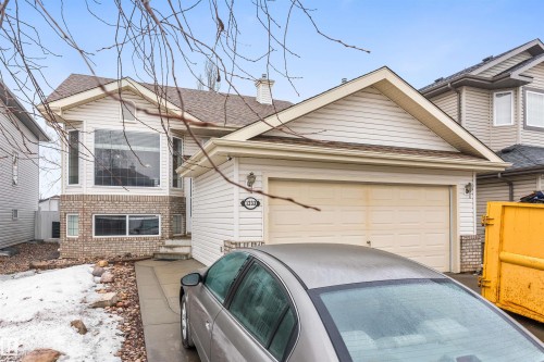 The property features white siding and brick detailing on the facade, a two-car garage, and a driveway - 1233 Ormsby Lane, Edmonton, AB - Outdoor