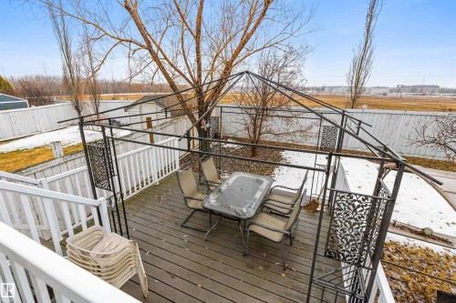 The property features a wooden deck with white railings, a metal gazebo structure, and a patio table with chairs - 1233 Ormsby Lane, Edmonton, AB - Outdoor With Deck Patio Veranda