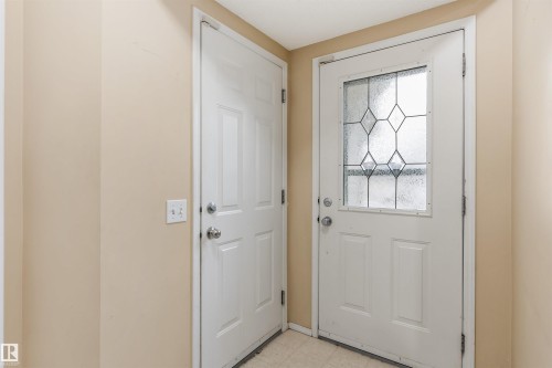 The property features a white door with decorative glass inserts, complemented by another white door and light-colored walls - 1233 Ormsby Lane, Edmonton, AB - Indoor Photo Showing Other Room
