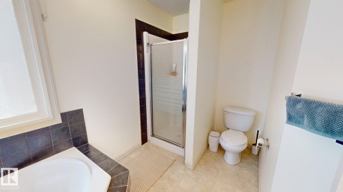 Bathroom featuring a shower with a clear glass door, a toilet, and a bathtub with dark tiled surround - 1609 Hodgson Crest, Edmonton, AB - Indoor Photo Showing Bathroom