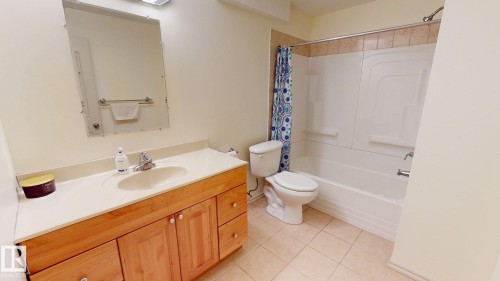 Full bathroom featuring a vanity with a light wood cabinet and light-colored countertop, a toilet, a bathtub with a shower, and tiled flooring - 1609 Hodgson Crest, Edmonton, AB - Indoor Photo Showing Bathroom