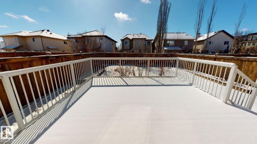 The property features a spacious outdoor deck with white railings, offering views of the surrounding neighborhood and a clear blue sky - 1609 Hodgson Crest, Edmonton, AB - Outdoor With Exterior