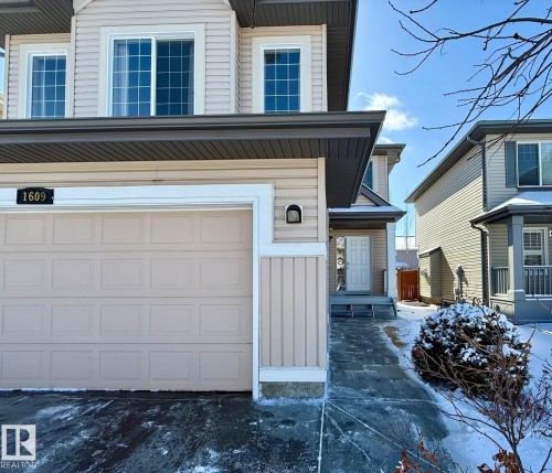 The property features a front-facing garage with a paneled door, a paved driveway, and a front entrance with steps - 1609 Hodgson Crest, Edmonton, AB - Outdoor