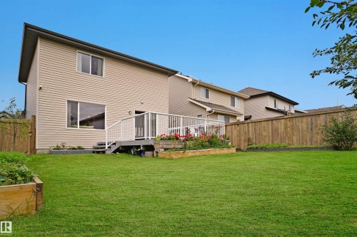 The property features a spacious backyard with a well-maintained lawn and a wooden privacy fence - 1609 Hodgson Crest, Edmonton, AB - Outdoor With Deck Patio Veranda With Exterior
