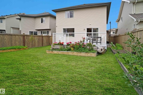 The property features a spacious lawn, a raised deck with white railings, and several garden beds - 1609 Hodgson Crest, Edmonton, AB - Outdoor