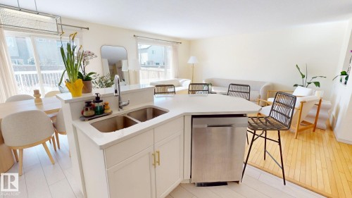 The kitchen features a double sink, stainless steel dishwasher, and a breakfast bar with seating - 1609 Hodgson Crest, Edmonton, AB - Indoor Photo Showing Other Room