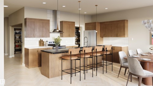 The kitchen features wood cabinetry, a large island with seating, a stainless steel refrigerator, and pendant lighting - 1729 Crossbill Loop, Edmonton, AB - Indoor