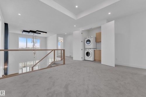 This open area features soft grey carpeting and recessed lighting - 503 Creekside Bay, Leduc, AB - Indoor Photo Showing Laundry Room