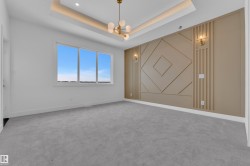 Spacious room featuring light grey carpeting, a large window, and a decorative wall with sconces - 
