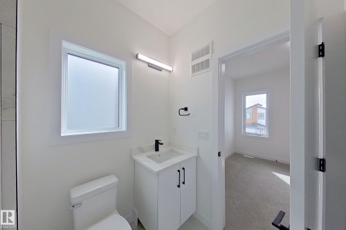 This bathroom features a white vanity with a rectangular sink and a matte black faucet - 8425 Mayday Link Link, Edmonton, AB - Indoor Photo Showing Bathroom