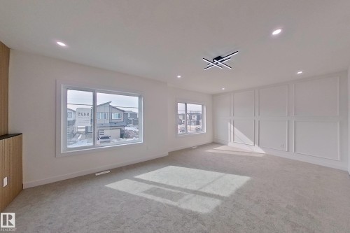 This inviting living space features carpeting, recessed lighting, and a modern ceiling light fixture - 8425 Mayday Link Link, Edmonton, AB - Indoor