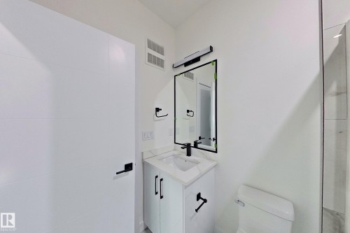 Bathroom featuring a modern vanity with a white countertop and a rectangular sink, a black framed mirror, and a toilet - 8425 Mayday Link Link, Edmonton, AB - Indoor Photo Showing Bathroom