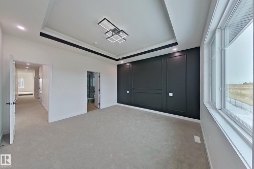 This room features a decorative accent wall, light grey carpeting, and a modern ceiling light fixture - 8425 Mayday Link Link, Edmonton, AB - Indoor Photo Showing Other Room