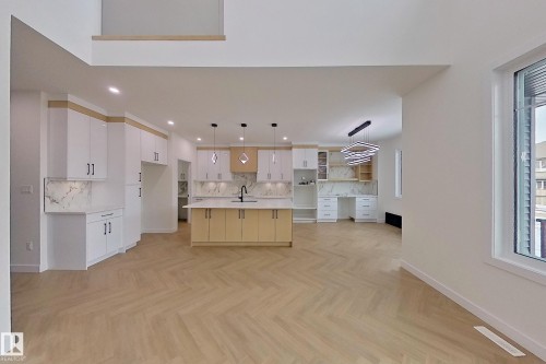 Open concept kitchen with a central island, modern pendant lighting, and herringbone pattern flooring - 8425 Mayday Link Link, Edmonton, AB - Indoor