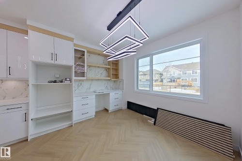 This bright room features a large window, stylish modern light fixture, and light-toned herringbone flooring - 8425 Mayday Link Link, Edmonton, AB - Indoor