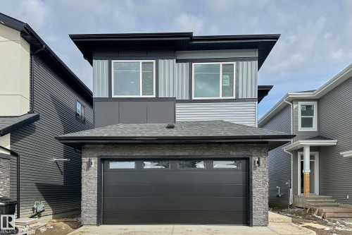 The property features a modern exterior with a mix of light and dark siding, a dark garage door, and stone accents around the garage - 8425 Mayday Link Link, Edmonton, AB - Outdoor