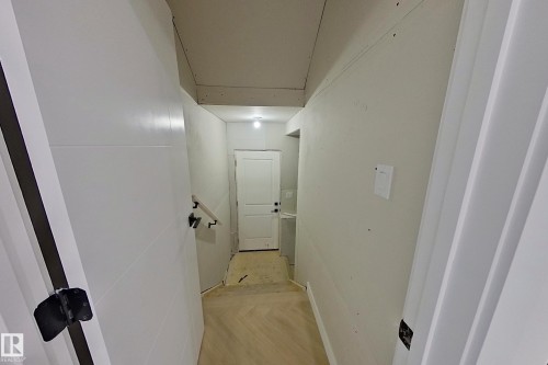 Hallway featuring a light wood floor, white walls, and a white door with a black handle - 8425 Mayday Link Link, Edmonton, AB - Indoor Photo Showing Other Room