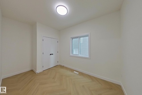 This room features light-colored herringbone flooring, white walls, and a window with horizontal blinds - 8425 Mayday Link Link, Edmonton, AB - Indoor Photo Showing Other Room
